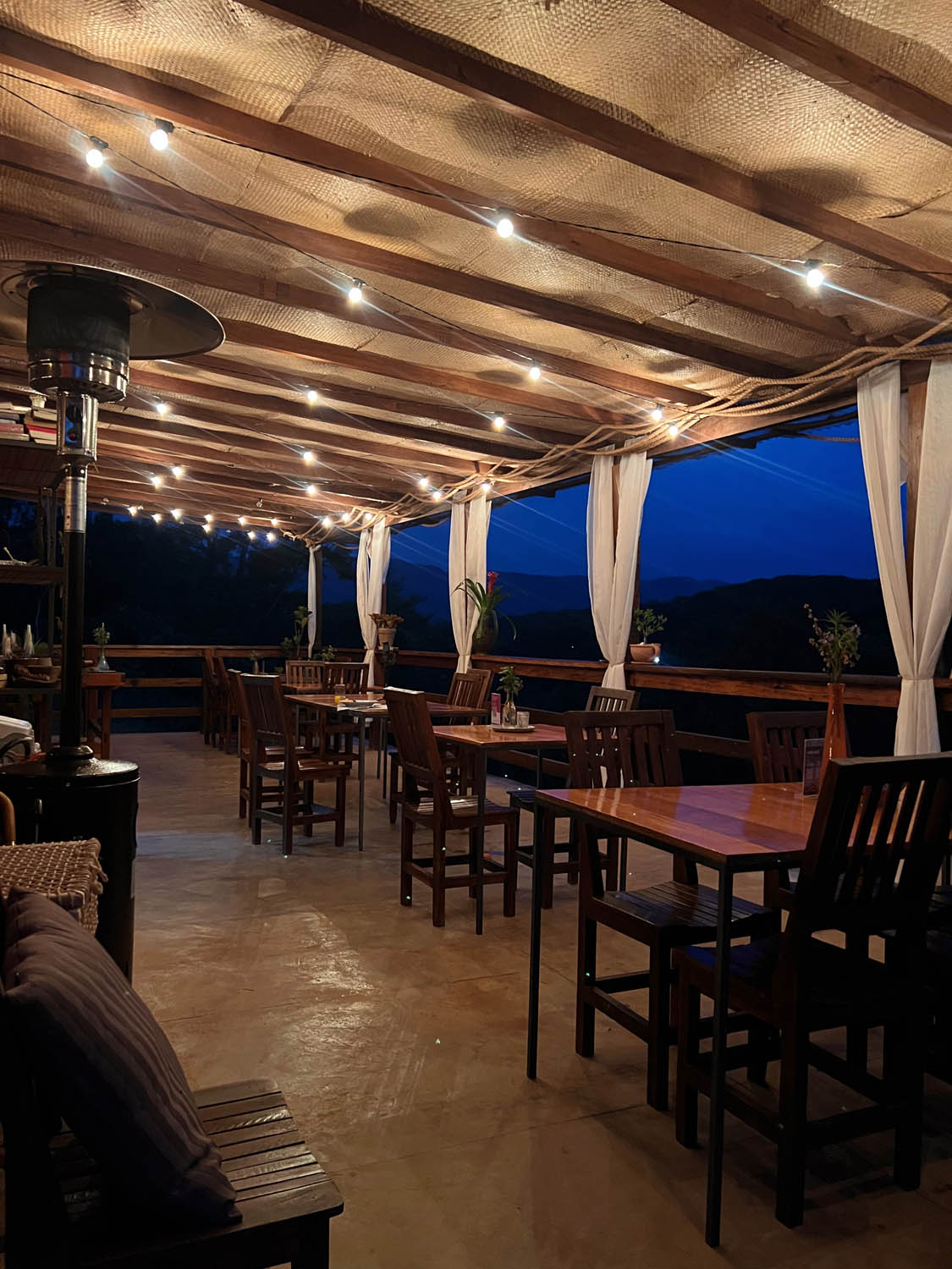 Varanda do restaurante iluminada à noite com vista para as montanhas
