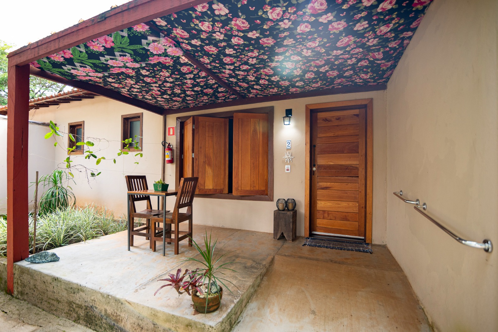 Varanda de entrada da suíte com teto floral e mesa externa