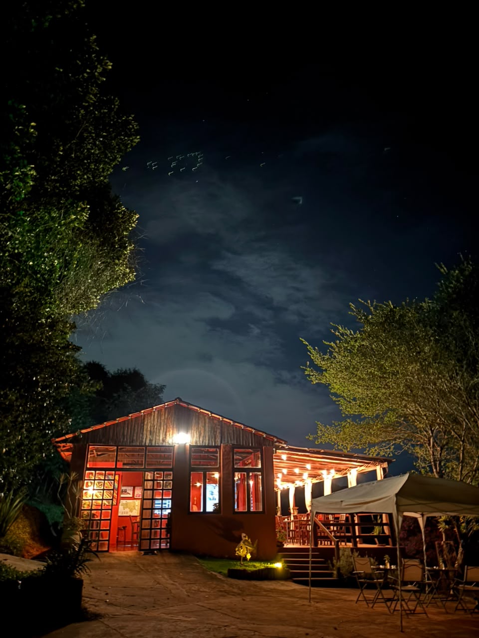 Fachada da pousada à noite com luzes quentes